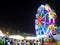 Bright neon light ferris wheel with unidentified crowed moving around in large THAI national street fair LOY KRATHONG