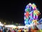 Bright neon light ferris wheel with unidentified crowed moving around in large THAI national street fair LOY KRATHONG