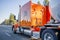 Bright orange big rig semi truck transporting tank semi trailer for transportation of liquid and liquefied chemical cargo running