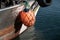 Bright orange buoy hanging from bow of an old fishing boat in the harbor