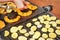 Bright orange butternut squash pieces grilled on electric grill, woman hands moving vegetables, blurred potato chips also cooked