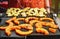 Bright orange butternut squash pieces seasoned with spices grilled on electric grill, blurred potato chips prepared in background