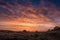 Bright Orange Clouds Glow Above Three Tents