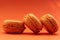 Bright orange color french macaroon cookies on gradient red background