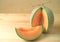 Bright orange color juicy ripe cantaloupe melon sliced from whole fruit isolated on wooden table