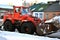 Bright orange excavator tractor cleaning snow on the road along residential houses, snowy winter in Kharkiv