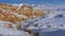 Bright orange hills and snow-capped mountains against the blue sky