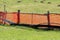 Bright orange makeshift improvised fence made of nylon net and wooden poles surrounded with uncut grass and molehills