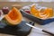 A bright orange pumpkin cut into pieces lies in a baking dish and on a chopping wooden board next to a knife