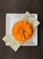 Bright Orange Pumpkin sits on Square Plate and Napkin