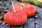 Bright orange pumpkins on an old wooden table with dry autumn leaves