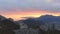 A bright orange sunset over a coastal mountain range under an overcast sky with clouds. Amazing spectacle aerial view