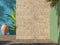Bright painted wall and natural stone travertine wall with green tropical leaves, sunlight with shadows. Summer, spring background