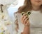 Bright photo of child with green fidget spinner in hands, sitting near flowers, white clothes and background