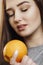 Bright picture of beautiful woman with orange halves, girl face with languid look, fashion model, concept fruits and healthy food