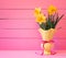 Bright Pink Boards Background with Yellow Daffodils in Vintage Vase with space for copy, text or words