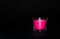 Bright pink candle in a glass jar on a black background. The candle is burning. Extinguished candle. Smoke from the candle. Hearth