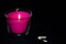 Bright pink candle in a glass jar on a black background. The candle is burning. Extinguished candle. Smoke from the candle. Hearth