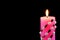 Bright pink candle, lit on a black creative background. The candle illuminates, and a symbol of faith, hope, Christmas holiday and