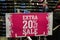 Bright pink Extra 20 percent off sale sign at shoe shop