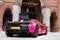 Bright pink McLaren luxury racing car parked outside the St. Pancras Renaissance Hotel in King\\\'s Cross, central London.