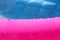 Bright pink paddling pool surface with water drops on it