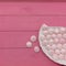 On a bright pink plank surface, there is a white platter with small delicate pink meringues.