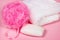 Bright pink soap and sponge for a bath with white towel on rose color background. Woman accessories for skin care and hygiene