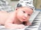 Bright portrait of cute 14 days newborn baby boy in funny cap lying and looking around