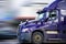 Bright Purple Bonnet Semi Truck Tractor with Reflection Driving on the Road for Delivery Commercial Cargo