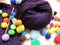 Bright purple knitting yarn and colorful pompoms 2020.