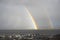 Bright rainbow high in sky over the sea during dark storm
