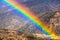 Bright rainbow on a rainy day in southern California; hills and valleys covered in chaparral visible in the background; Los