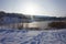 A bright ray of sun against the backdrop of a winter pond and city buildings