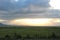 The bright rays of the setting sun shine through a huge cloud on the evening valley in the hilly steppe