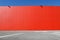 Bright red aluminium cladding wall with an asphalt road in front. Background for copy space