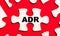 On a bright red background, white puzzles. In one of the pieces of the puzzle, the text ADR Alternative Dispute Resolution