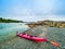 Bright red kayak on a pebble ocean beach