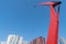 Bright red kinetic lamp posts surrounded by modernist high-rise architecture and blue sky