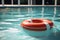 A bright red lifebuoy floats on the tranquil surface of the pool
