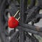Bright red lock in the shape of a heart on a black old railing of the bridge, love symbol
