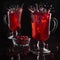 Bright red mulled wine with berries and splash in two glass wine glasses in black dark interior, square.