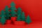 Bright red New Year background with three red cylinder podiums mockup, green paper spruces as forest in modern style.