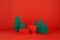 Bright red New Year background with two red cylinder podiums mockup, green paper spruces as forest in festive style.