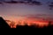 Bright red and orange and blue sunset sky against houses and bare trees silhouettes. Winter evening.