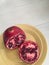 Bright red Pomegranate sliced on yellow plate on white table