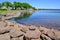 Bright red rocks forming barrier along Charlottetown Harbour with reflections on water surface