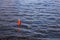 Bright red signal buoy in the dark blue ocean among the waves