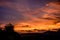 Bright red sunset over silhouetted houses.