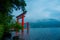 Bright red Torii gate submerged in the waters of Ashi lake, caldera with mountains on the background. Hakone Shrine, Kanagawa pref